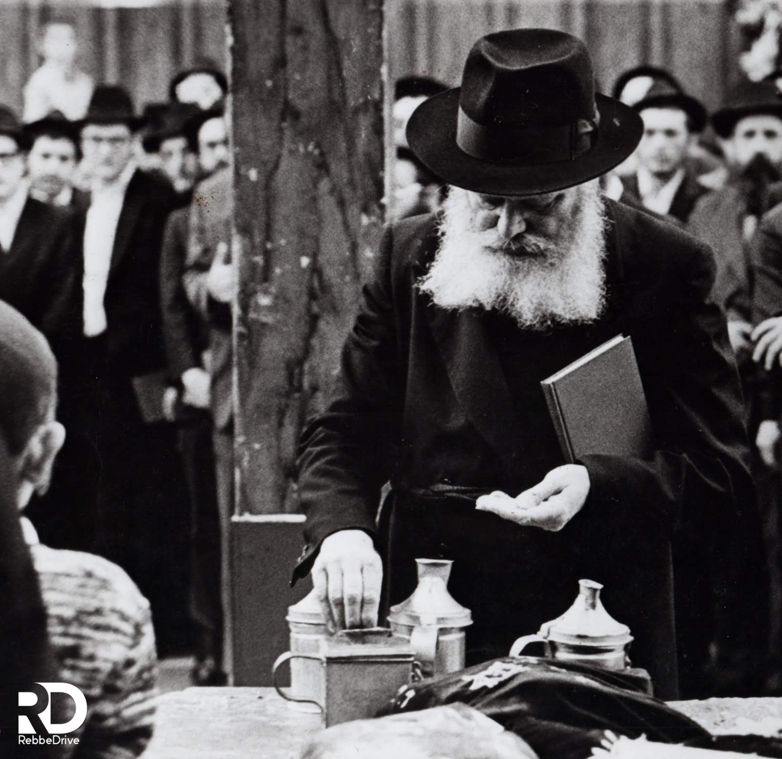 The Lubavitcher Rebbe giving coins to tzedakah.